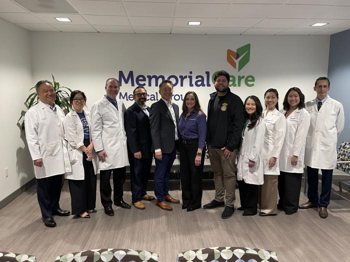 A group of doctors and city officials standing in the lobby of a primary care location in front of a sign that says "MemorialCare Medical Group"