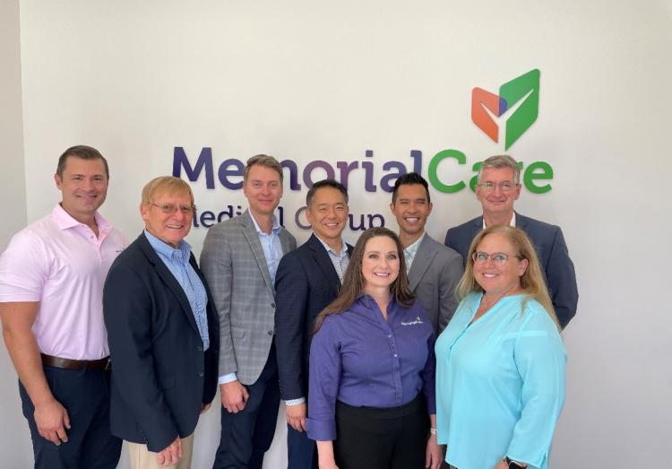 Various MemorialCare executives take a photo together in front of a MemorialCare Medical Group sign. 