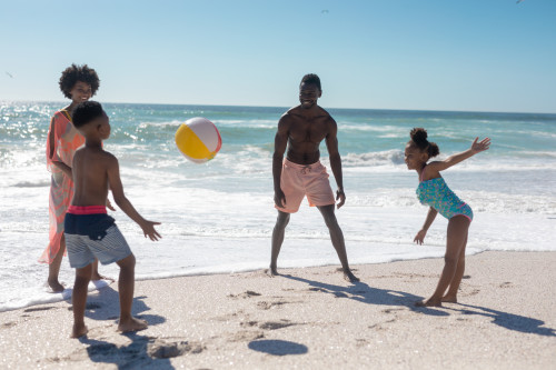 Family of four at beach playing with beach ball.