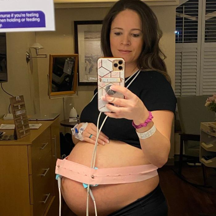 Woman holding iphone to take mirror selfie of her pregnant.