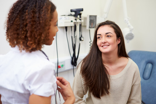 Teenage girl speaking to physician in medical office.