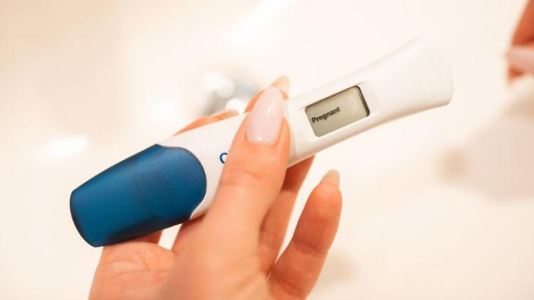 A positive pregnancy test held in someone's hand. 