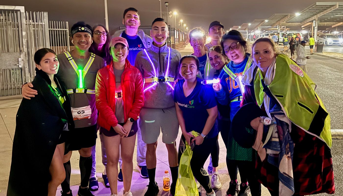 A group of runners standing in a parking lot wearing reflective gear.